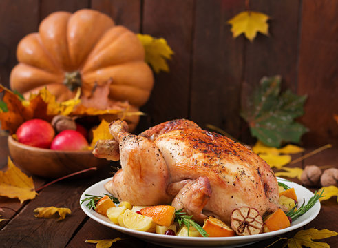 Roasted turkey garnished with cranberries on a rustic style table decorated with pumpkins, orange, apples and autumn leaf. Thanksgiving Day.