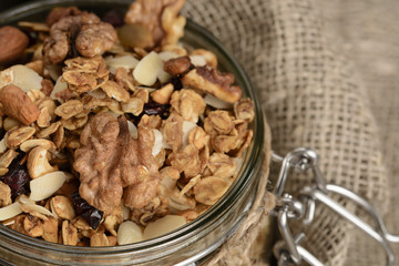 Homemade granola in open glass jar on rustic wooden background