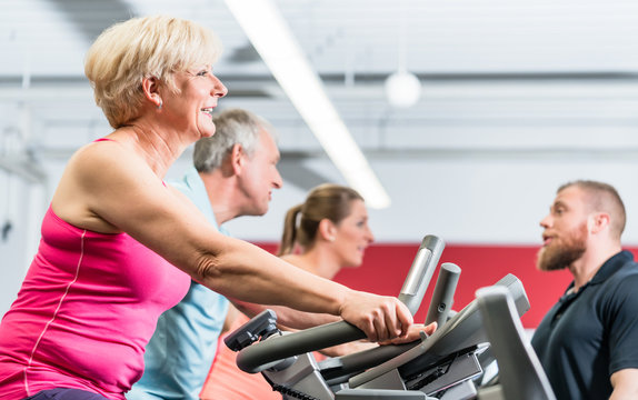 Senioren trainieren am Crosstrainer im Fitnessstudio mit Fitnesstrainer  Stock Photo | Adobe Stock