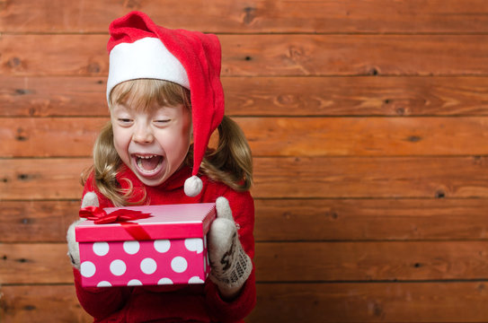 Happy child with a gift on a wooden background with copy space.
