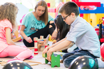 Niedliche Jungen und Mädchen in Kindergarten oder Vorschule spielen mit Holzspielzeug