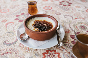 A baked rice dessert in a plate on the table next to a cup of fragrant hot tea in a cafe.