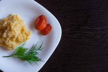 Millet porridge with dried apricots on white plate