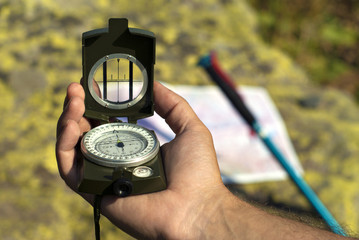 Professional geological compass in the man`s hand closeup. On a blurry background can distinguish a...