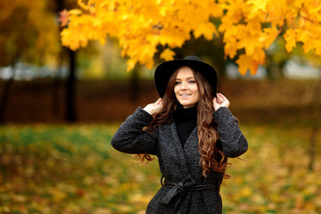 woman with autumn leaves in hand and fall yellow maple garden background