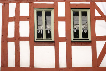 Fachwerkhaus mit schmalen Fenstern / Die Balkenkonstruktion und das Holzgerüst eines Fachwerkhauses mit zwei schmalen Holzfenstern.