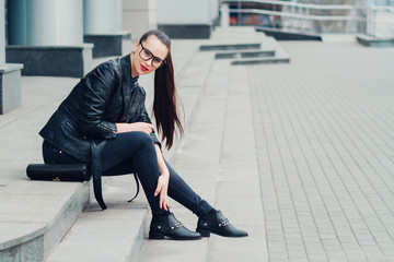 portrait of a young girl with glasses , beautiful girl on the street sitting on the stairs