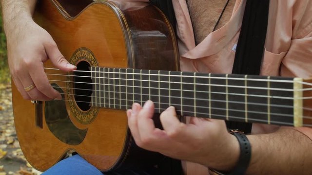 Guitarist intensive plays by classic acoustic guitar at autumn park