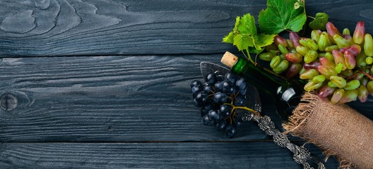 A bottle of wine and grapes. On a wooden background. Top view. Free space for your text.