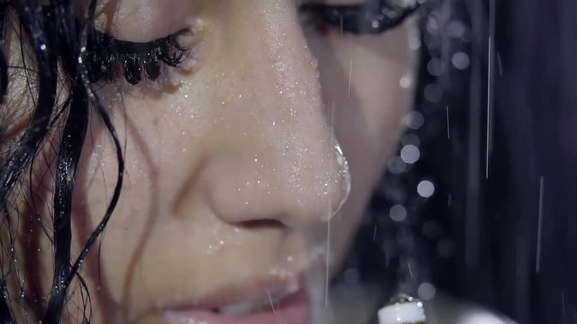 Close-up. Portrait of a young pretty girl with a heavily painted eyes. She inhales the scent of Oriental aromatic oils under water in the shower