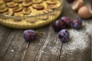 Homemade plum pie with fresh plums on wooden background