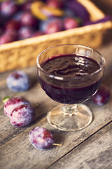 Homemade Plum jam with fruit on wooden background
