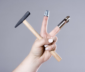Hand Holding a Small Hammer with Two Thimbles.