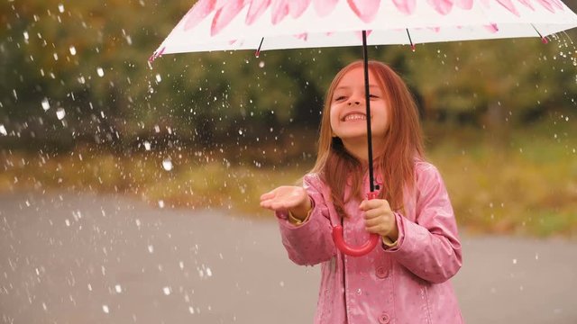 Cheerful girl with umbrella under rain