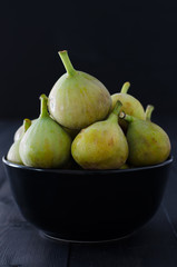 Figs in bowl on black background.