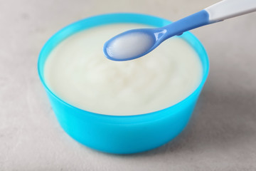 Spoon of baby porridge over bowl on table