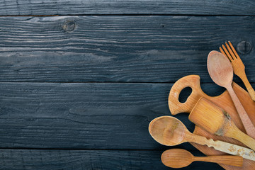 Wooden spoons, forks and shovels. On a wooden background. Top view. Free space for your text.