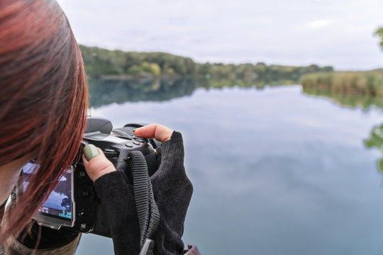 Woman photographer shoots an autumn landscape - a lake with a beach line