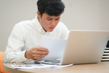 close up man hand holding paperwork for reading with stress and serious feeling , work hard and unhealthy concept