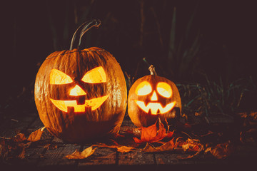 Halloween pumpkin with glowing face on a wooden background in a spooky forest night