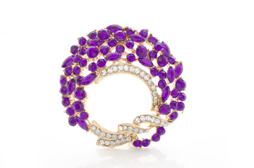 golden round brooch with purple diamonds isolated on white