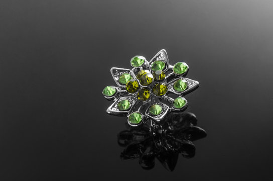 silver brooch with emeralds isolated on black