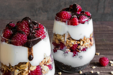 raspberry yogurt parfait in glasses with chocolate, granola and chia seeds