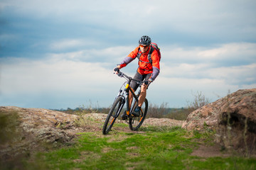 Naklejka na ściany i meble Cyclist in Red Riding Bike on the Rocky Trail. Extreme Sport and Enduro Biking Concept.