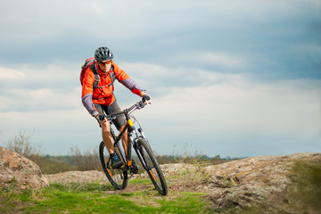 Naklejka na ściany i meble Cyclist in Red Riding Bike on the Rocky Trail. Extreme Sport and Enduro Biking Concept.