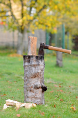 Old vintage axe is stuck in a piece of log wood used for chopping other wood.