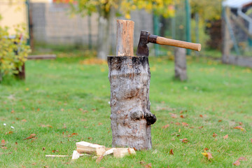 Old vintage axe is stuck in a piece of log wood used for chopping other wood.