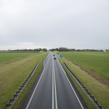 main road north of groningen city between green meadows in the north of the netherlands