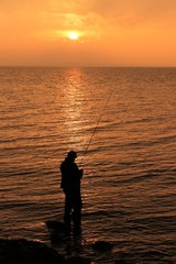 Angler an der Küste, goldene Lichtstimmung am Meer, Meerforellenangler