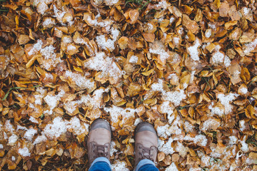 Leather Boots legs View on the Snow with Fallen leaves at autumn fall winter season.