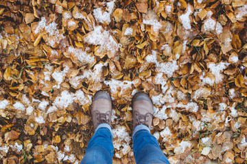 Leather Boots legs View on the Snow with Fallen leaves at autumn fall winter season.