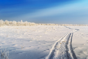 Winter landscape. Winter road, through a field covered with snow.