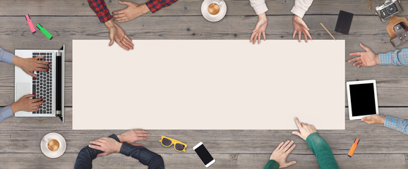 Business Teamwork concept - top view of six business people. White blank sheet of paper in the middle of the wooden table.