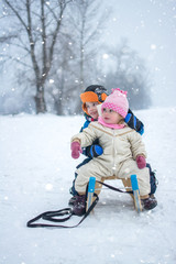Fototapeta na wymiar Little girl and boy enjoying sleigh ride in the nature.