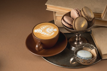French traditional cuisine - macaroon and coffee cappuccino with books background.