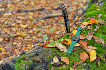 Male set - knives and watches. Black knife and smart watch in autumn forrest