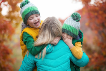 Obraz premium Two little boys gently hug his mother.A walk in the autumn woods. 