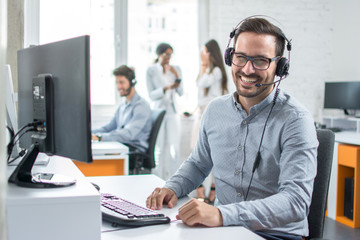 Happy young male customer support executive working in office. - Powered by Adobe