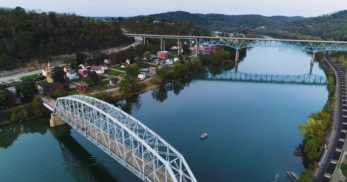 A daytime high angle reverse aerial establishing shot of the small town of Brownsville, PA - a Pittsburgh suburb. Bridges over the Youghiogheny River in the foreground.  	