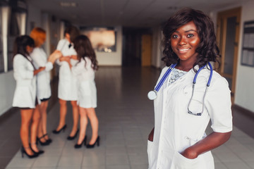 African American student medical worker, wearing a white coat, against the background of...