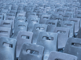 Infinitely many uniform grey plastic chairs on a big square prepared for a huge event