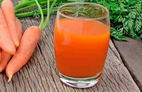 Carrot juice in a glass on rustic wooden table