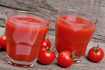 Glasses of fresh tomato juice on wooden table
