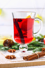 New Year's mulled wine in a glass on the background of twigs, candles and garlands.