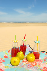 Bottles lemonade and fruit at beach