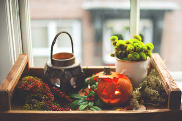 pumpkin and candles for the autumn holiday of Halloween, on a wooden tray at the window